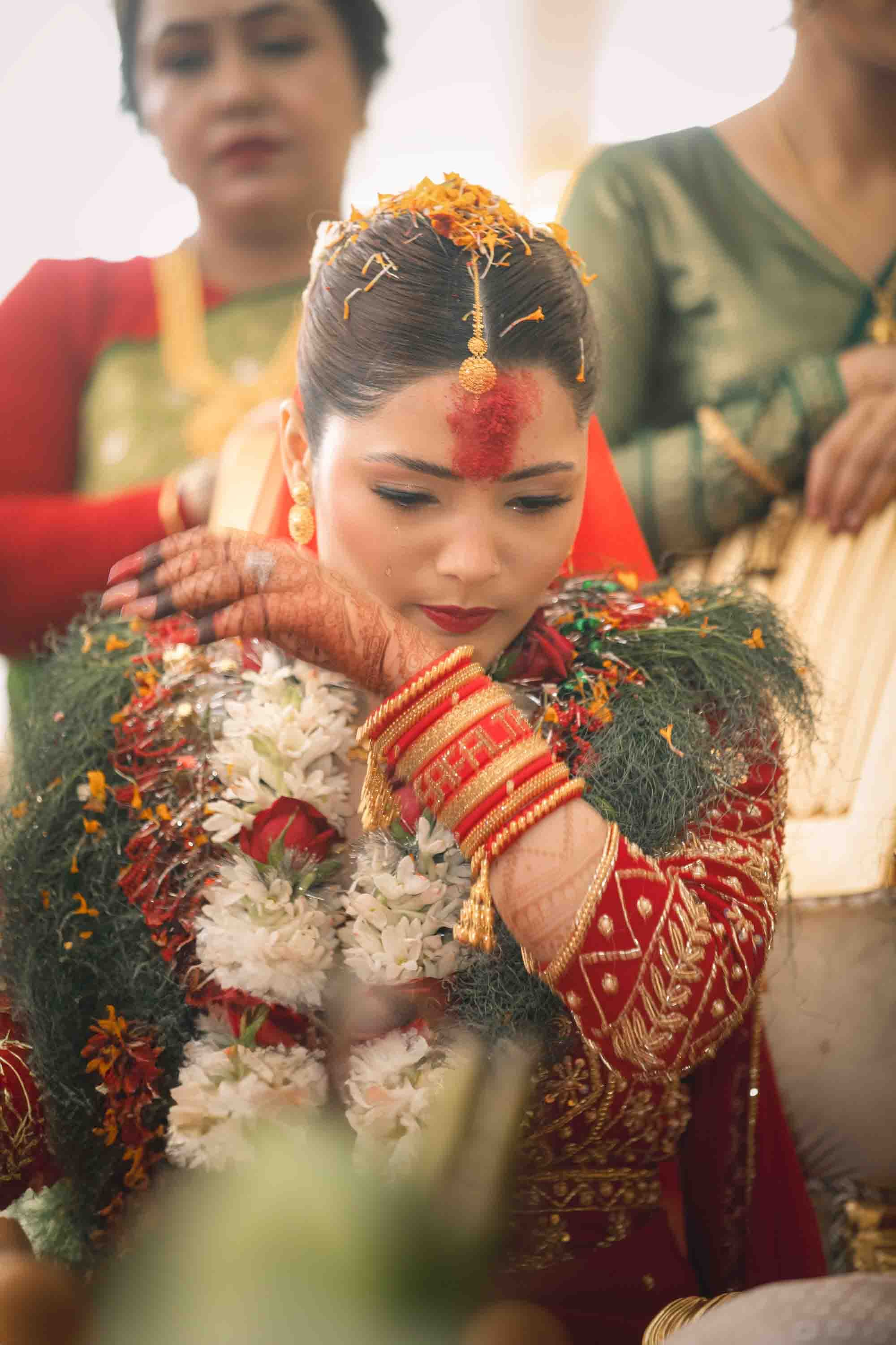 Beautiful Nepali bride sitting at decorated wedding venue table - bridal photography by Wedding Studio Nepal